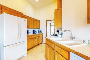 A kitchen with wooden cabinets, a white refrigerator, a double sink, and a dishwasher.