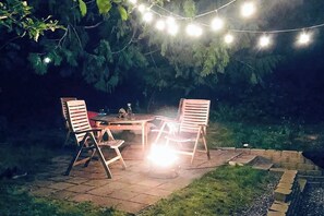 Een terras met een tafel en stoelen, omgeven door een stenen muur en beplanting.