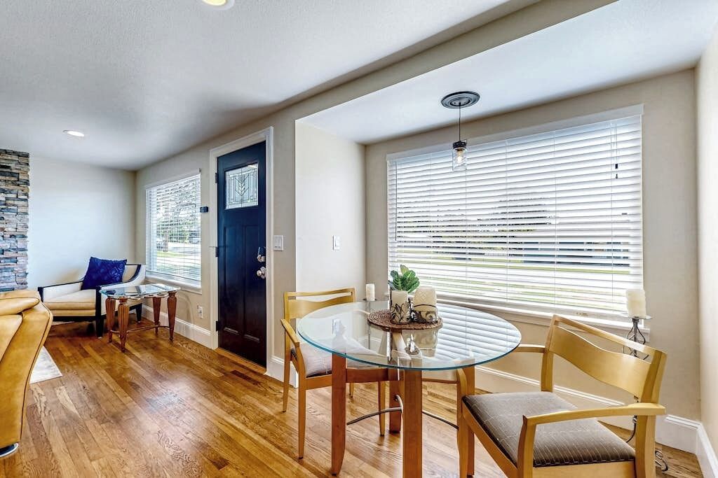 A dining area with a glass table, wooden chairs, and a black door.