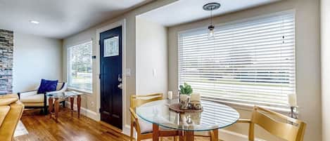 A dining area with a glass table, wooden chairs, and a black door.
