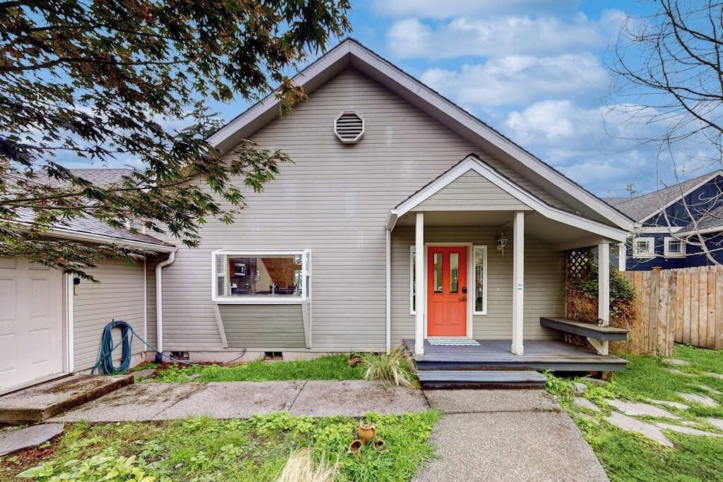 A residential house with a front porch, a garage, and a well-maintained lawn.