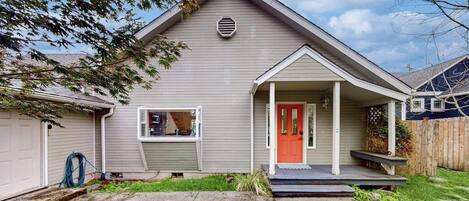 A residential house with a front porch, a garage, and a well-maintained lawn.