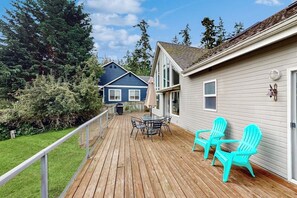 A wooden deck with outdoor furniture, a railing, and a house with a light-colored exterior. - Stunning Saratoga Passage Waterfront Home with Sunrise Views and Private Deck (Coupeville)