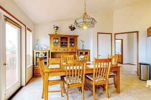 Un coin repas avec une table et des chaises en bois, un lustre et un buffet aux portes vitrées.