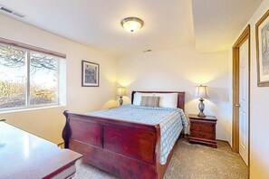 Une chambre à coucher avec un lit en bois, deux lampes de chevet, une table de chevet, une fenêtre et une porte.