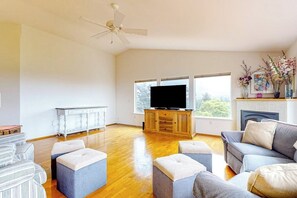 A spacious living room with a flat-screen TV, wooden flooring, and a fireplace.