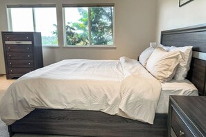 A bedroom with a bed, dresser, and windows.
