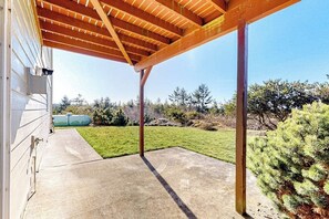 Un patio couvert doté d’un sol en béton et de poutres en bois au-dessus.