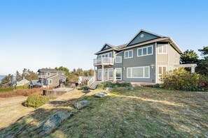 A two-story house with a balcony, a deck, and a view of the sea. - Stunning Dog Friendly Waterfront Villa with Sunset Views and Fireplace (Oak Harbor)