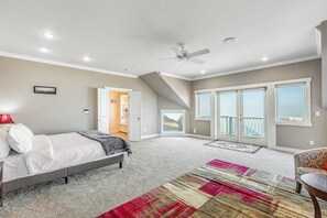 A bedroom with a bed, a ceiling fan, a large window, and a view of the outdoors. - Stunning Dog Friendly Waterfront Villa with Sunset Views and Fireplace (Oak Harbor)