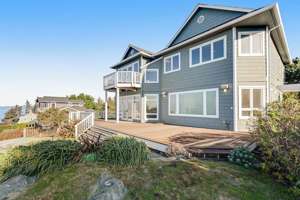 A two-story house with a balcony, large windows, and a wooden deck.