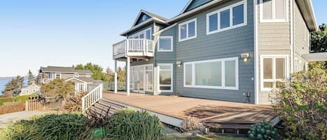 A two-story house with a balcony, large windows, and a wooden deck.