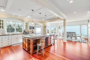A spacious kitchen with a large island, wooden flooring, and a view of the outdoors. - Stunning Dog Friendly Waterfront Villa with Sunset Views and Fireplace (Oak Harbor)