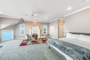 A bedroom with a bed, a fireplace, a ceiling fan, and a view of the outdoors. - Stunning Dog Friendly Waterfront Villa with Sunset Views and Fireplace (Oak Harbor)