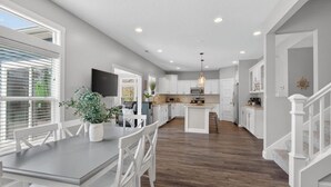 Una cocina amplia con armarios blancos, una isla central y un comedor con mesa y sillas.