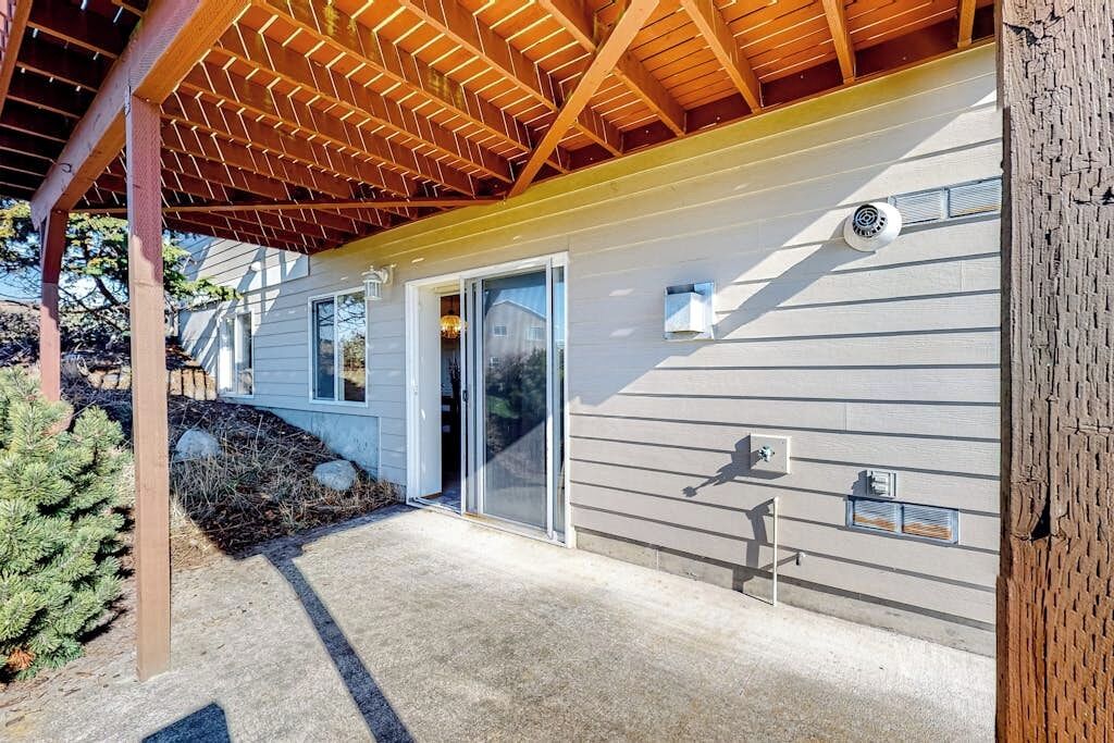 A residential building with a covered porch, a sliding glass door, and a visible outdoor light fixture.