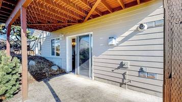 A residential building with a covered porch, a sliding glass door, and a visible outdoor light fixture.