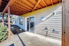 A residential building with a covered porch, a sliding glass door, and a visible outdoor light fixture.