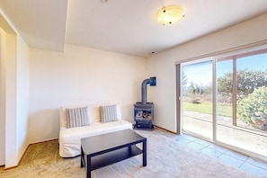 A room with a sofa, a table, and a wood-burning stove. - La Cana Street Leisure In Law Suite (Coupeville)