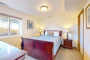 Une chambre à coucher avec un lit en bois, des lampes de chevet, une fenêtre et une porte.