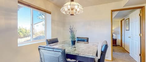 Un coin repas avec une table et des chaises, un lustre et une plante en pot.