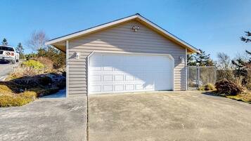 A single-story building with a garage, a concrete driveway, and a chain-link fence.
