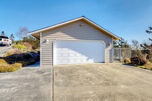 A single-story building with a garage, a concrete driveway, and a chain-link fence.