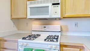 Una cocina con microondas blanco, estufa y armarios de madera.
