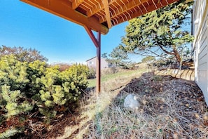 A wooden pergola structure, a landscaped garden with shrubs, and a house in the background. - La Cana Street Leisure In Law Suite (Coupeville)