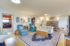 A spacious living room with a sofa, armchairs, a coffee table, and a fireplace.