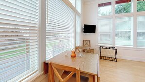 A room with a wooden table and chairs, a flat-screen TV mounted on the wall, and large windows with blinds. - Restorative tiny home with amazing outdoor space, central location, and free Wifi (Langley)