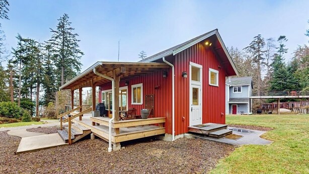 A red wooden house with a covered porch, a front door, and a small attached garage. - Restorative tiny home with amazing outdoor space, central location, and free Wifi (Langley)