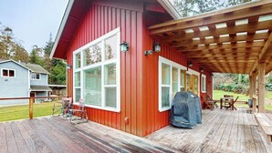 A red building with a wooden deck, outdoor furniture, and a barbecue grill. - Restorative tiny home with amazing outdoor space, central location, and free Wifi (Langley)