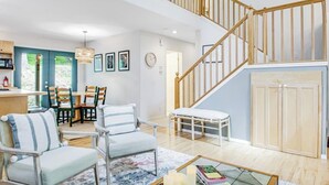 Un vaste espace de vie comprenant un escalier, un coin repas et une vue sur l’extérieur.