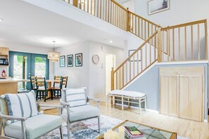 A spacious living area with a staircase, a dining area, and a view of the outdoors. - Dreamy Retreat in the Woods with Firepit, Fireplace, Free and Large Deck (Eastsound)