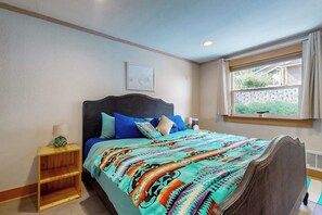 A bedroom with a bed, a nightstand, a window with curtains, and a wall-mounted picture. - Stunning Oceanfront Getaway in Langley with Private Patio and WiFi (Langley)
