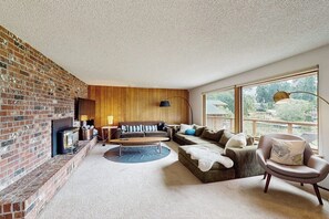 A living room with a brick wall, wooden paneling, a sofa set, a coffee table, and a large window with a view.