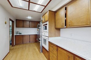 Eine Küche mit Holzausstattung, einer weißen Arbeitsplatte und einem eingebauten Backofen.
