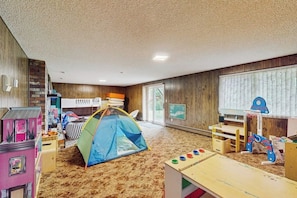 Ein Zimmer mit Spielbereich, darunter ein Zelt, Spieltische und Spielzeug.