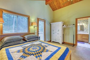 A bedroom with a large bed, a wardrobe, and a bathroom visible through an open door.