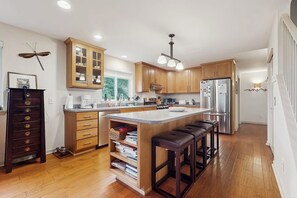 Una cucina moderna con mobili in legno, un'isola centrale con sgabelli ed elettrodomestici in acciaio inossidabile.