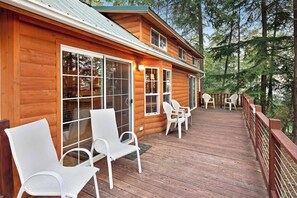 A wooden cabin with a deck, large windows, and outdoor seating.
