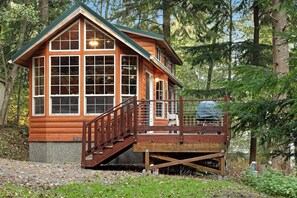 A wooden cabin with a porch and a staircase leading to a deck.