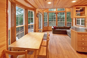 Un interior de madera con una mesa de comedor, sillas, un sofá y una zona de cocina.