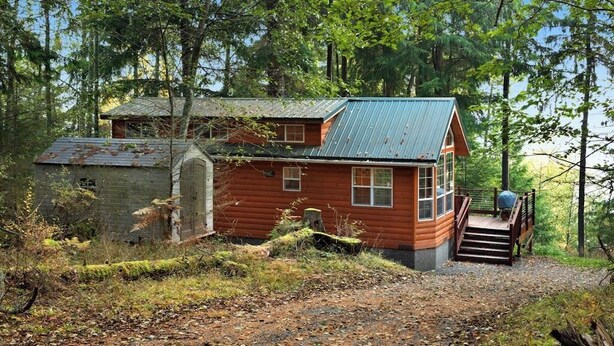 A cabin with a metal roof, wooden walls, and a wooden staircase leading to a porch. - Cozy 1BR Waterfront Cabin with Mountain Views (Eastsound)