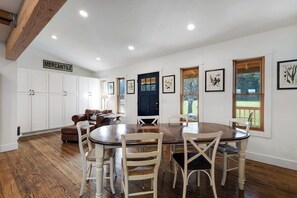 A dining area with a wooden table and chairs, a black door, and white cabinets labeled 'MERCANTILE'.