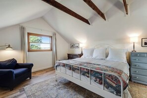 A bedroom with a bed, a dresser, a nightstand, a lamp, a chair, and a window.
