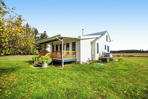 A single-story house with a porch, a small deck, and a grassy yard.