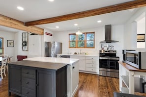 A modern kitchen with wooden beams, stainless steel appliances, and a large island.