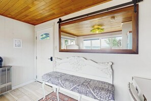 A room with a white bench, a wooden ceiling, a window with a view, and a door. - Whimsical 1940s Waterview Gem with Sweeping sea views, Wildlife, & Near Town (Langley)